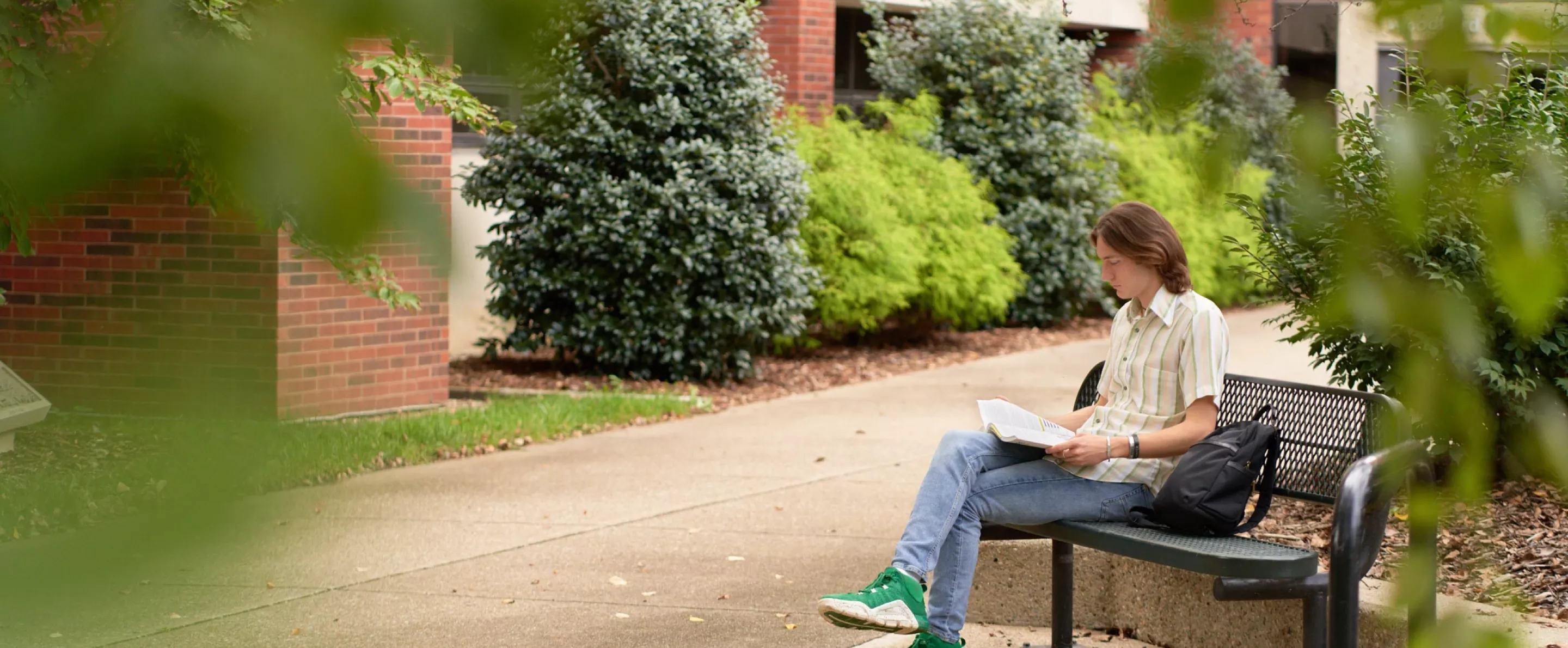 Student sitting on the bench outside the CEHD looking at his academic materials.