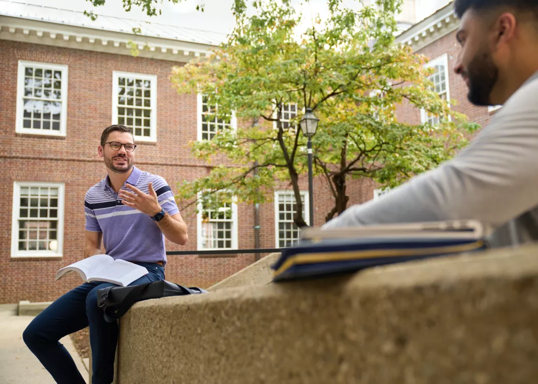 Two students having a socially distanced conversation in the courtyard at the Brandeis School of Law.