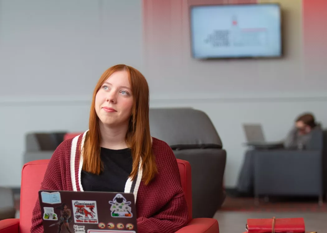 A student pauses in thought while working on a laptop in the Belknap Academic Building